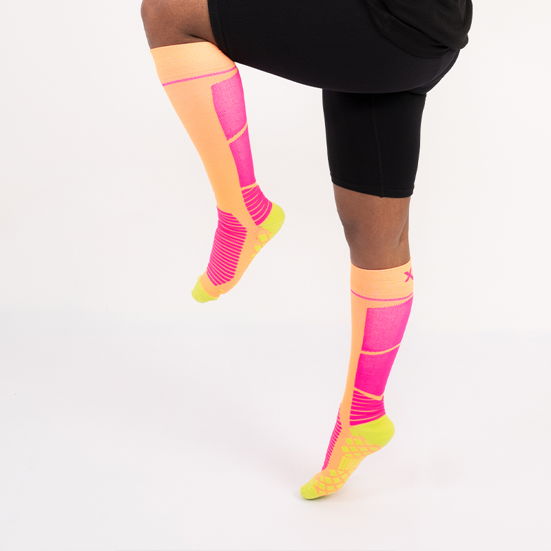 Beine mit neon orange-pinken kniehohen Sport Kompressionsstrümpfen